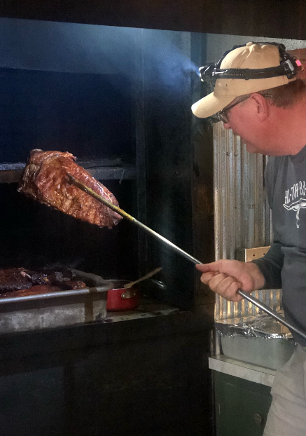 Pitmaster pulling brisket from the smoker at Hilltop Bar-B-Que
